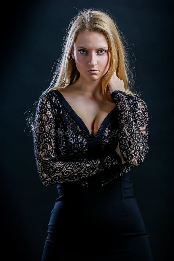 Blonde girl on a black background in dark guipure dress
