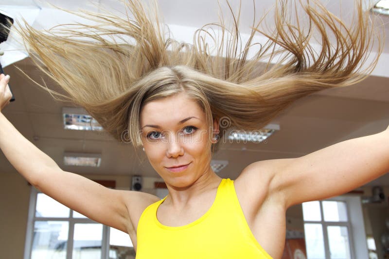 Blonde girl with flying hair jumping in gym