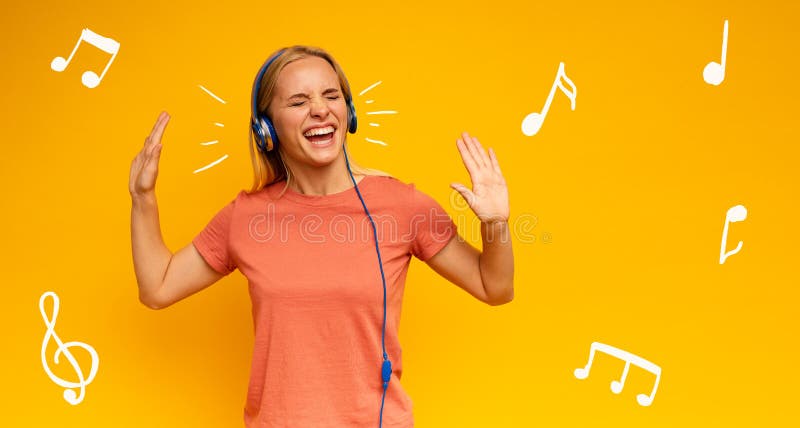 Blonde girl listens to music with headset. Joyful expression on yellow background stock images Blonde girl listens to music with headset. Joyful expression on yellow background stock images