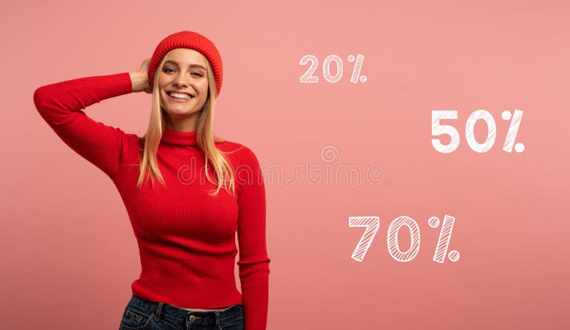 Blonde girl smiles with red hat and cardigan. Pink background for blank space for your discount text royalty free stock photography Blonde girl smiles with red hat and cardigan. Pink background for blank space for your discount text royalty free stock photography