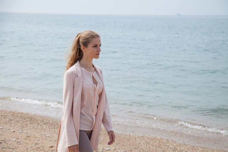 Blonde girl walks along the beach of the sea coast