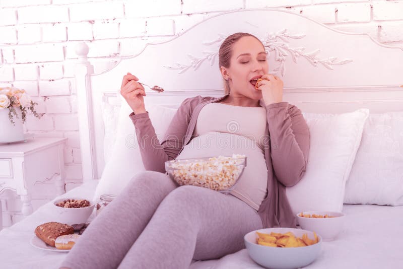 Blonde knappe zwangere vrouw die in comfortabele kleren met genoegen eten royalty-vrije stock fotografie Blonde knappe zwangere vrouw die in comfortabele kleren met genoegen eten royalty-vrije stock fotografie