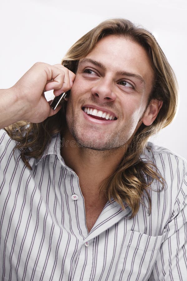 Young man , long blonde hair speaking over the phone wearing casual shirt. Young man , long blonde hair speaking over the phone wearing casual shirt