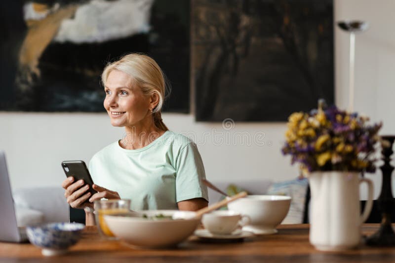 Blonde Mature Woman Using Laptop And Cellphone While Having Lunch Stock Image Image Of Food