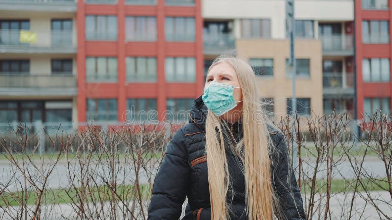 Blonde meisje in een medisch masker op de bank stock foto Blonde meisje in een medisch masker op de bank stock foto
