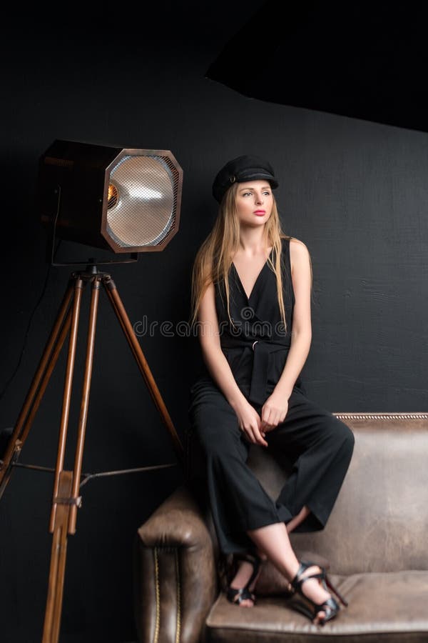 Blonde model posing in dark studio. Young attractive fashion model posing on dark background.