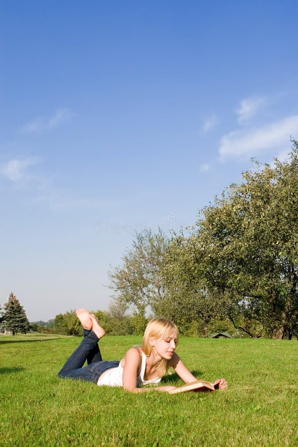 Blonde reads book in the park royalty free stock image
