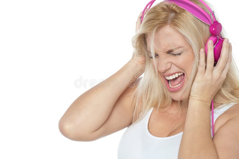 Blonde screaming while listening to rock music. Holding her pink headphones.