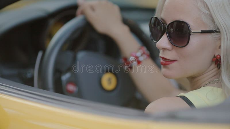 Blonde in sits behind the wheel of cabriolet