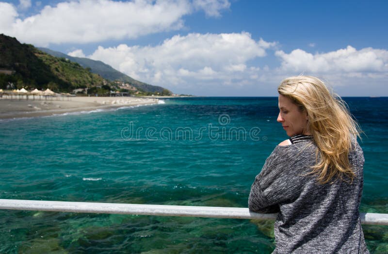 Blonde woman outdoor, azure blue sea background, beach and mountan