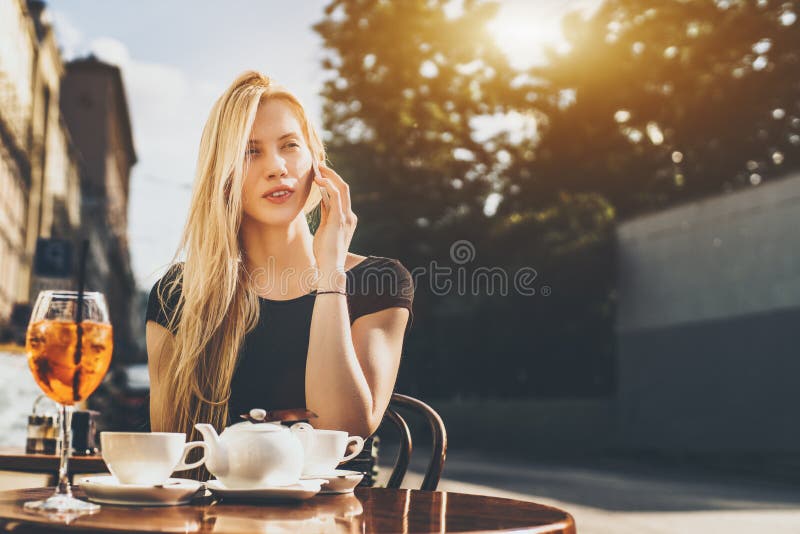 Blonde woman speaking on smartphone in cafe