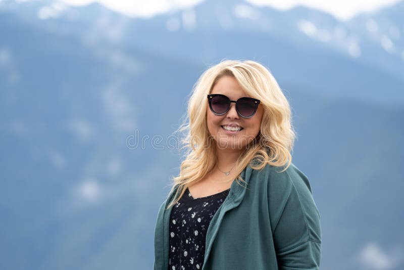 Blonde woman wearing sunglasses poses for a portrait with the Cascade Mountains in background stock image Blonde woman wearing sunglasses poses for a portrait with the Cascade Mountains in background stock image