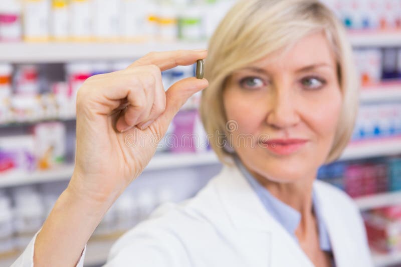 Blondeapotheker in laboratoriumlagen die pil tonen stock foto Blondeapotheker in laboratoriumlagen die pil tonen stock foto