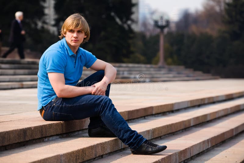 Blonder Mann, der draußen sitzt stockfoto Blonder Mann, der draußen sitzt stockfoto