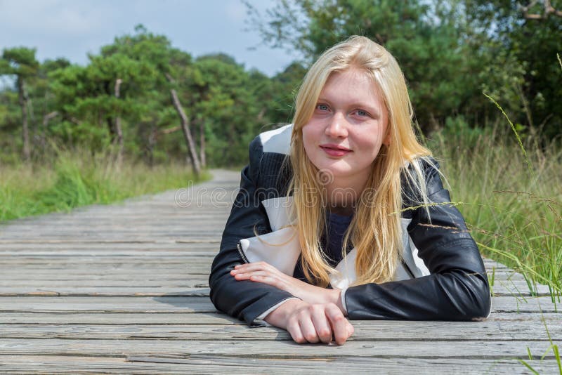 Blondes Mädchen, das auf hölzernem Weg in der Natur liegt lizenzfreie stockbilder Blondes Mädchen, das auf hölzernem Weg in der Natur liegt lizenzfreie stockbilder
