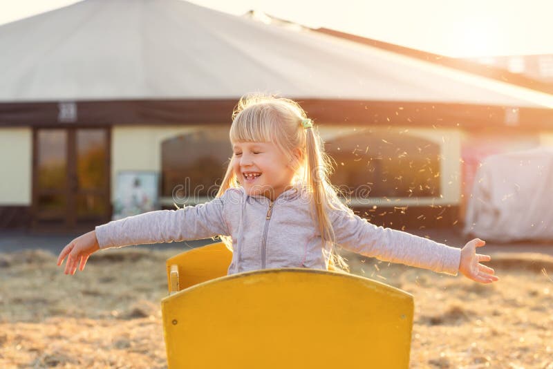 Blondes Mädchen des entzückenden netten Kaukasiers Kinder, dasim hölzernen Wagen hat werfendes Stroh oder Heu des Spaßes am Bauer lizenzfreies stockbild Blondes Mädchen des entzückenden netten Kaukasiers Kinder, dasim hölzernen Wagen hat werfendes Stroh oder Heu des Spaßes am Bauer lizenzfreies stockbild