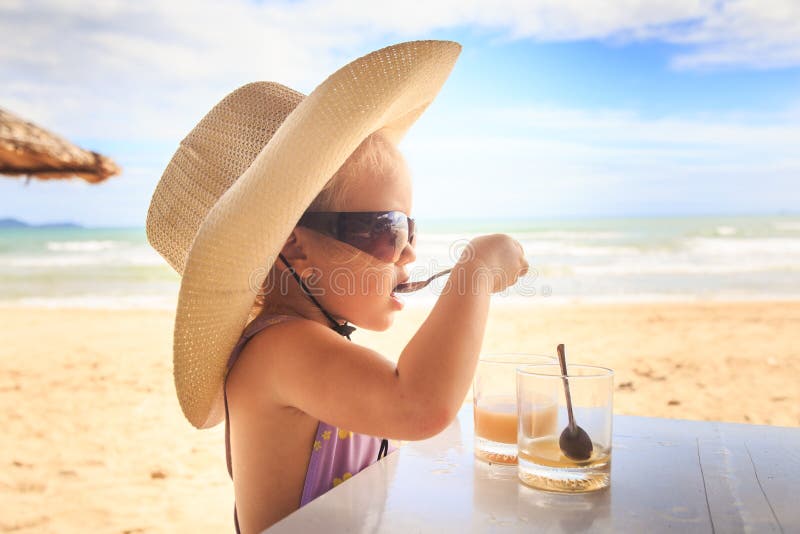 Blondes Mädchen im Großen Hut-Sonnenbrille-Getränk-Saft mit Löffel stockfotos Blondes Mädchen im Großen Hut-Sonnenbrille-Getränk-Saft mit Löffel stockfotos