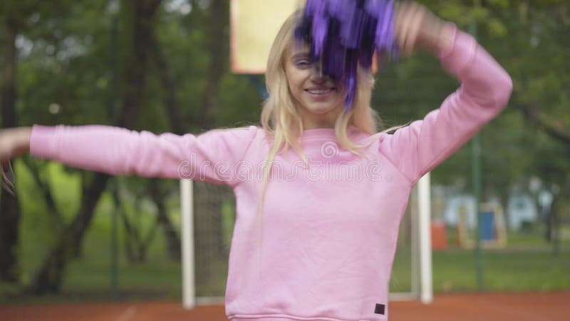 Blondes selbstbewusstes Frauentanzen mit Pompoms auf Gericht im Freien. Porträt der positiven überzeugten kaukasischen Cheerleader stock video