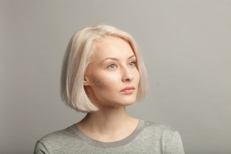 Blondevrouw die in grijze t-shirt net op grijze achtergrond kijken royalty-vrije stock afbeelding Blondevrouw die in grijze t-shirt net op grijze achtergrond kijken royalty-vrije stock afbeelding