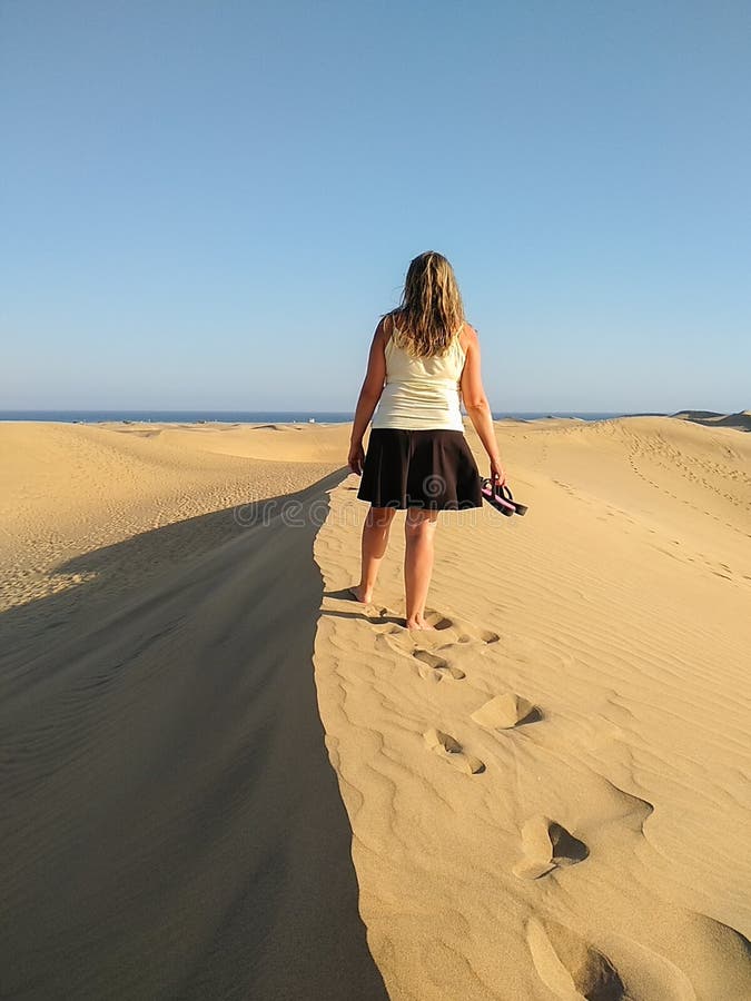 Blondine, die an der Spitze einer D?ne beim Betrachten des Meeres auf dem Horizont dem Sonnenuntergang gehen Das Gehen des barf?? lizenzfreies stockfoto Blondine, die an der Spitze einer D?ne beim Betrachten des Meeres auf dem Horizont dem Sonnenuntergang gehen Das Gehen des barf?? lizenzfreies stockfoto