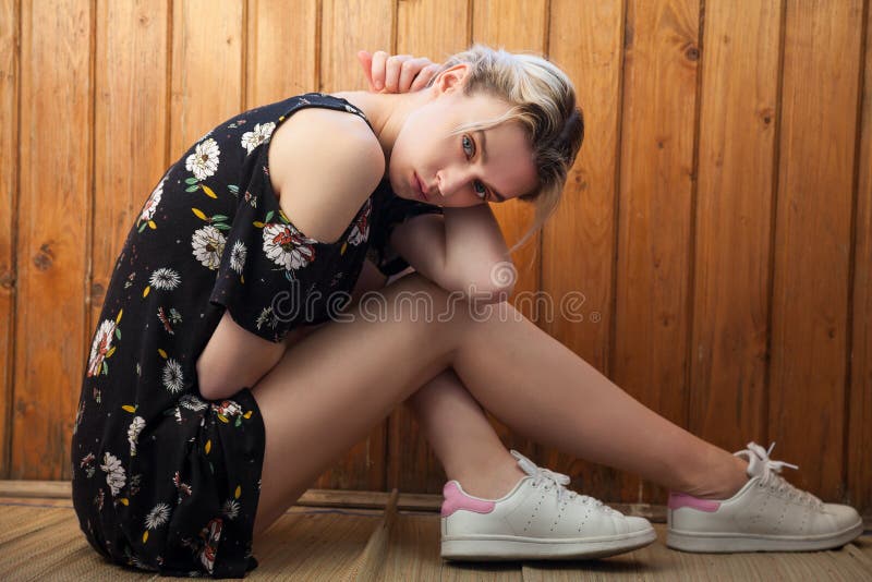 Fashionable woman blonde in dress with flowers sits on the floor. Fashionable woman blonde in dress with flowers sits on the floor