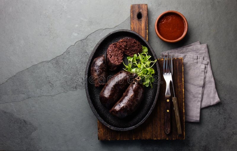 Bloody sausages - chilean preta on iron plate, top view, grey slate background