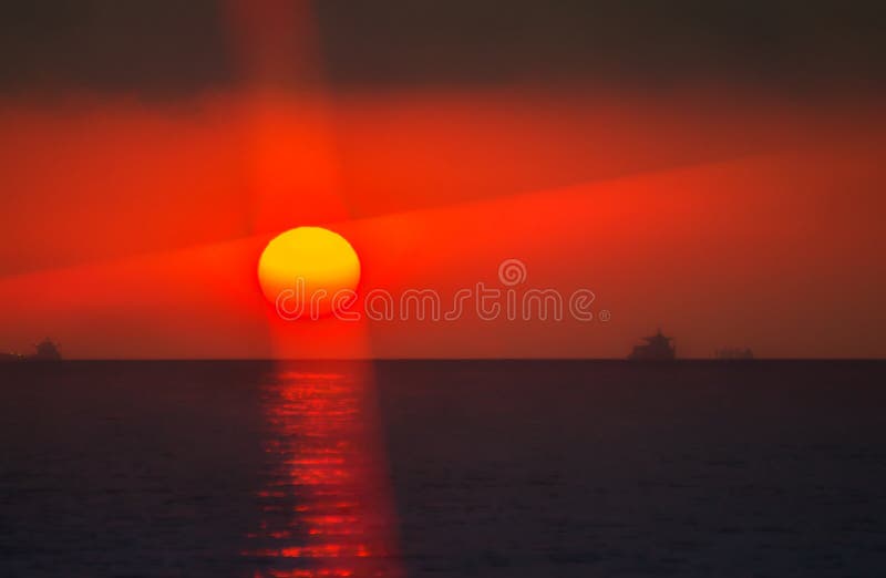 Sanguinosa sole al tramonto, tra il mare e il cloud.