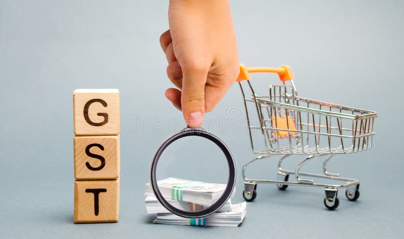 Bloques de madera con las mercanc?as de la palabra GST y el impuesto de servicios, el dinero y una carretilla del supermercado Im foto de archivo Bloques de madera con las mercanc?as de la palabra GST y el impuesto de servicios, el dinero y una carretilla del supermercado Im foto de archivo