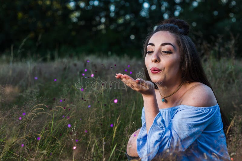 My friend blows purple coloured metalic hearts confetti from her hand during a photoshoot in a meadow near Liverpool. My friend blows purple coloured metalic hearts confetti from her hand during a photoshoot in a meadow near Liverpool