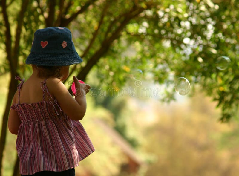 Little blond blowing bubbles in park