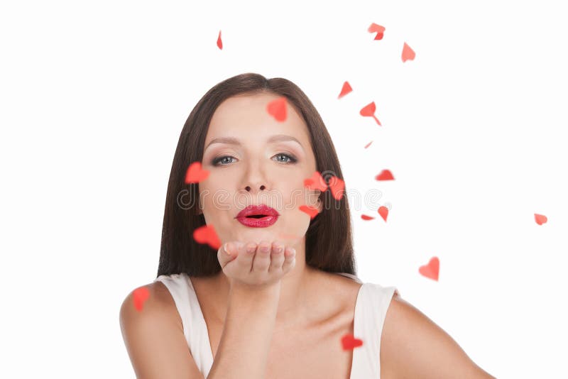 Beautiful young woman blowing paper hearts and smiling while isolated on white. Beautiful young woman blowing paper hearts and smiling while isolated on white