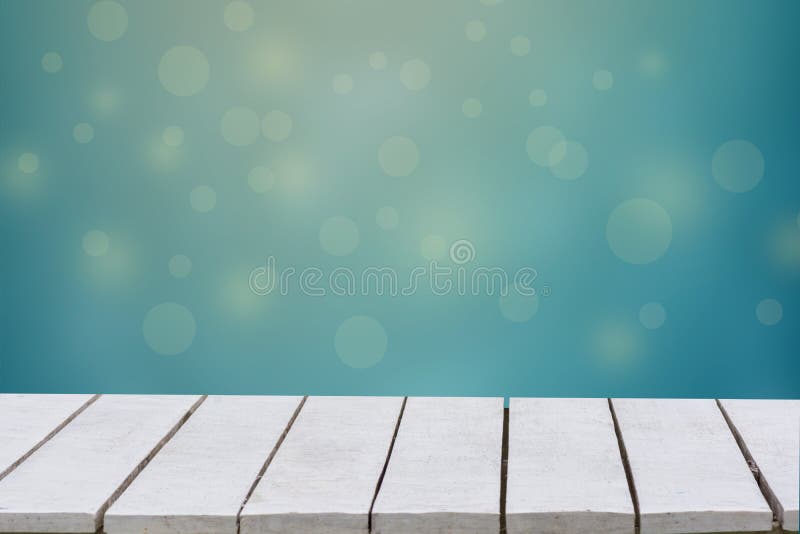 Blue background with selective focus. The green background has a bokeh leaf and grass on a white wooden floor. Empty table empty s