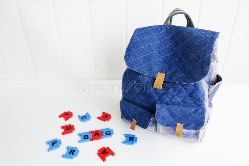 Blue Bag with Puzzle Letters on White Table. Hand Made Backpack for