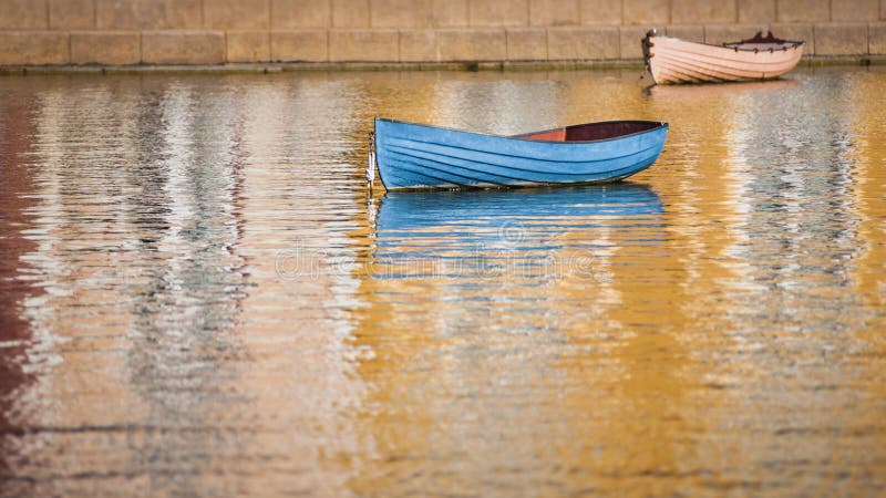 Blue boat in harbor with reflections of color from surrounding buildings on the water. Blue boat in harbor with reflections of color from surrounding buildings on the water