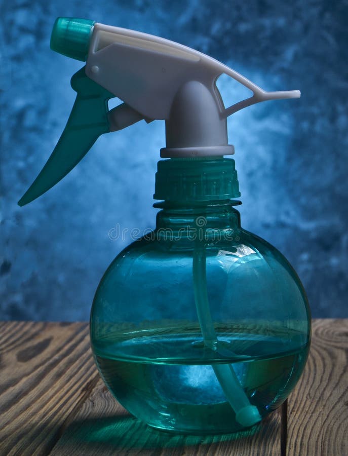 A Blue Bottle of a Transparent Sprayer on a Table on the Background of