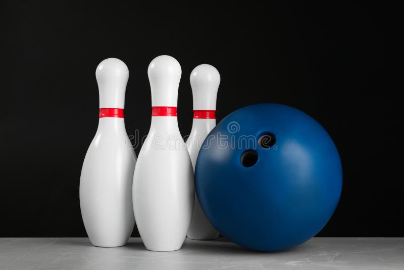 Blue bowling ball and pins on grey marble table stock photos.