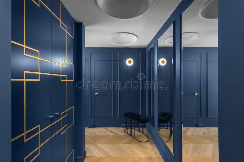 Blue classic wall decor in modern interior with golden line decor elements, wooden floor, hidden doors. royalty free stock photo