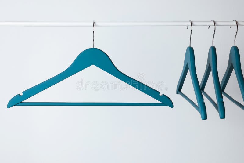 Blue Clothes Hangers on Metal Rail Against Light Background Stock Image
