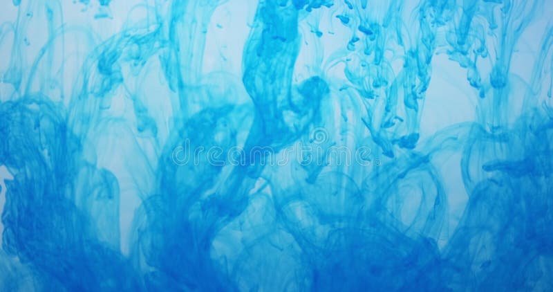 Blue color paint ink drops in water at white background. Inky cloud flowing underwater. Abstract isolated cloudy smoke