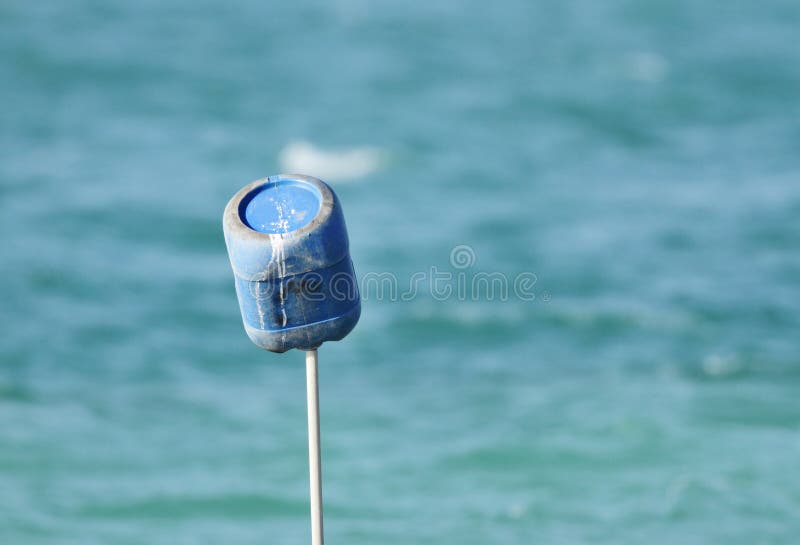 Blue container on a pipe highlighting the fishing net in sea stock photography