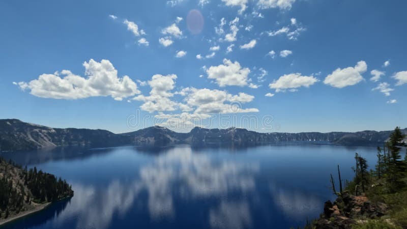 Blue Crater Lake where Reflection in the Water Reflect Sky and Clouds as a Mirror with Mountains in the Background an Establishing