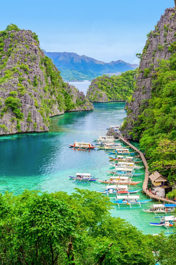 Blue crystal water in paradise Bay with boats on the wooden pier at Kayangan Lake in Coron island, Palawan, Philippines