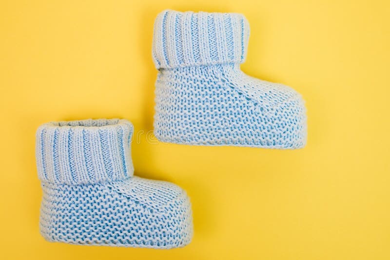 Blue cute booties for newborn baby. Baby boy shoes on yellow background. royalty free stock image