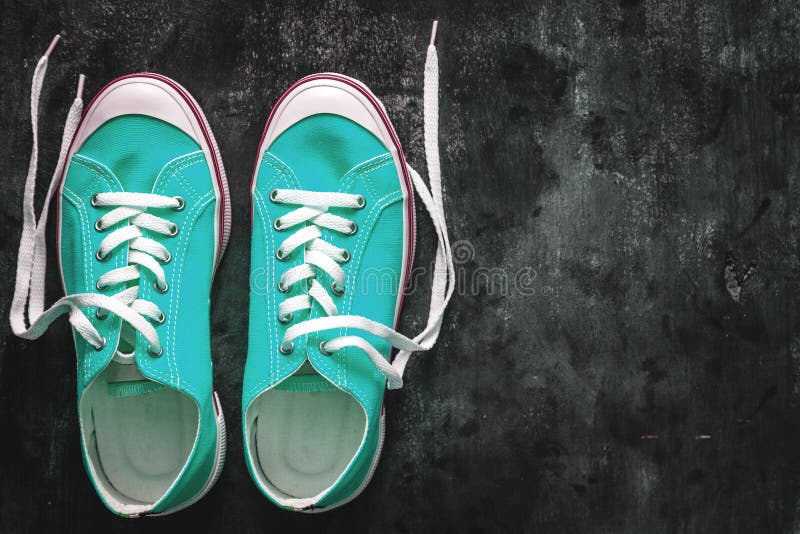 Blue-cyan-green-turquoise sneakers with untied laces on a dark concrete background. Copy space. View from above. royalty free stock photo Blue-cyan-green-turquoise sneakers with untied laces on a dark concrete background. Copy space. View from above. royalty free stock photo