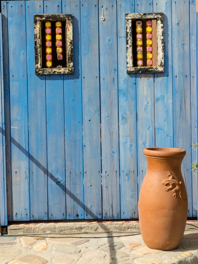 An old fashioned blue wooden door and rustic clay vase at a Mexican hacienda. An old fashioned blue wooden door and rustic clay vase at a Mexican hacienda.