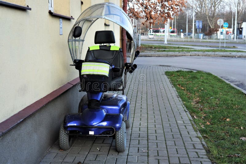 Blue four wheeled mobility scooter- electric wheelchair parked outside a house