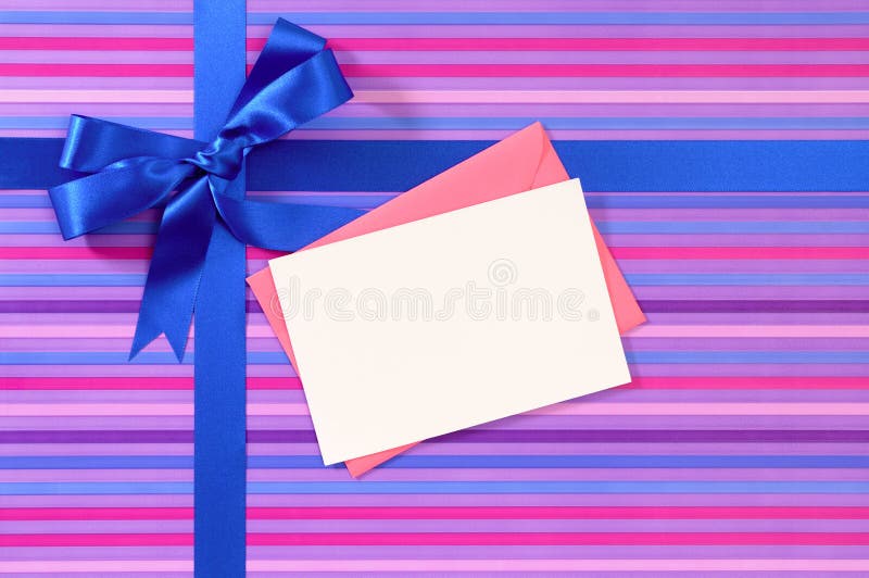 Blue gift ribbon bow on candy stripe wrapping paper, blank Christmas or birthday card and envelope, copy space. Blue gift ribbon bow on candy stripe wrapping paper, blank Christmas or birthday card and envelope, copy space