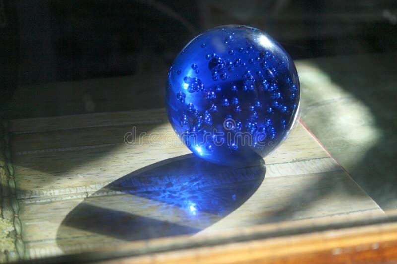 Blue glass crystal ball with bubbles. Magic sphere with light shing through the ball globe.