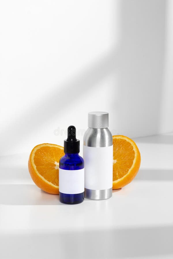Blue glass and silver metal skin care bottle decorate with fresh half oranges on window light white background royalty free stock photography Blue glass and silver metal skin care bottle decorate with fresh half oranges on window light white background royalty free stock photography