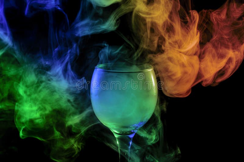 Abstract art. Hookah blue - green and orange smoke into the cocktail glass on a white background. Witch potion background for Halloween. Unusual bar drink. Drink in the glass with the effect of dry ice. Abstract art. Hookah blue - green and orange smoke into the cocktail glass on a white background. Witch potion background for Halloween. Unusual bar drink. Drink in the glass with the effect of dry ice.